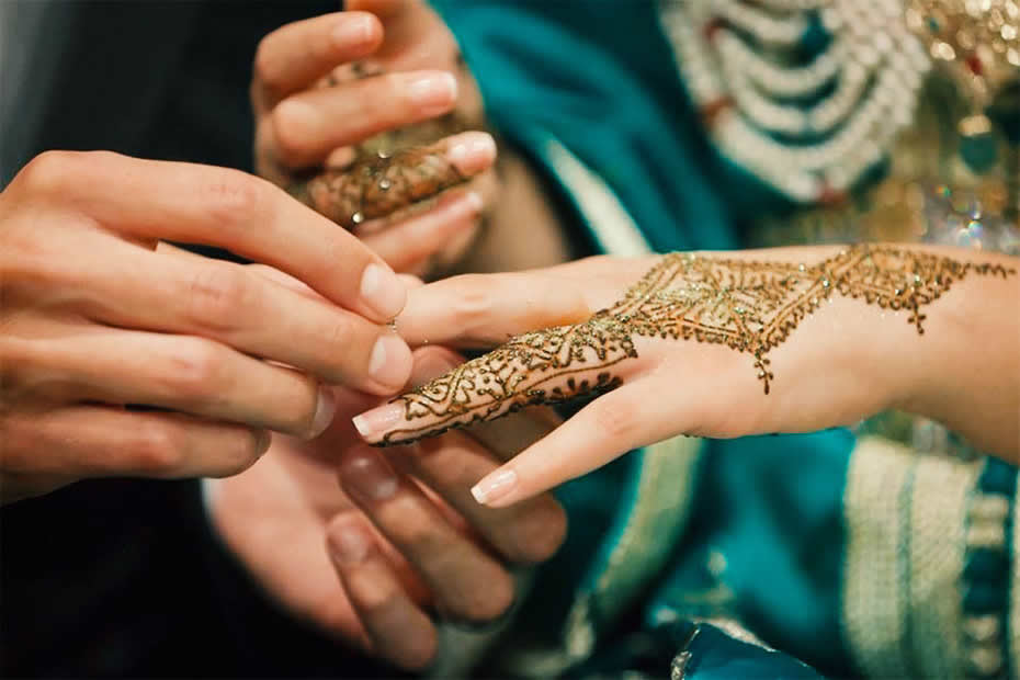 Hand's bride with henna tattos in Morocco during a wedding while husband wear her the ring