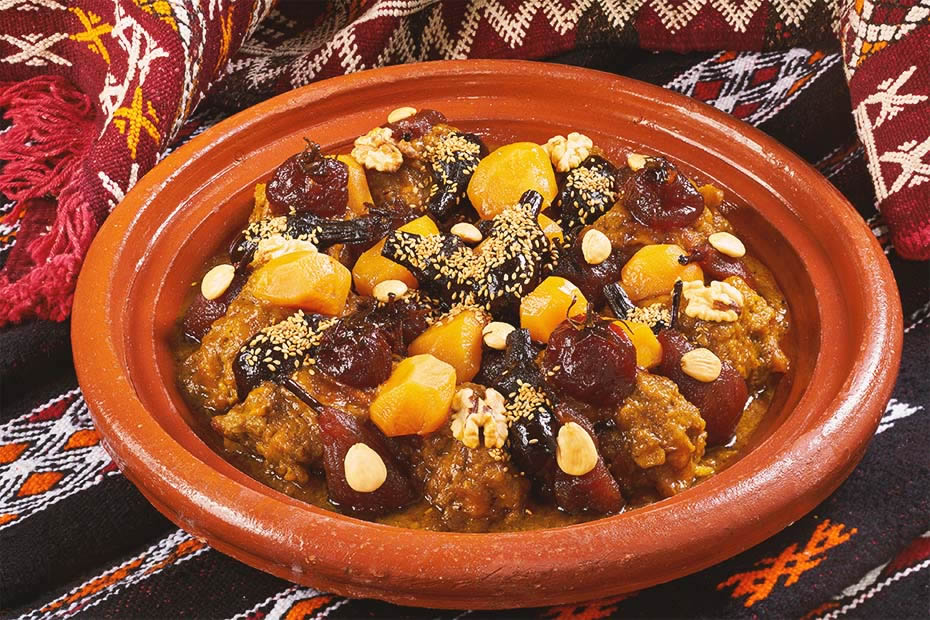 A sweet Moroccan meat tajine with dried fruit and pears decorated with some sesame seeds and grilled almonds