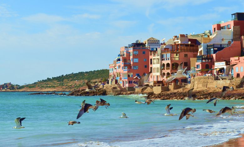 A beautiful and colorful city of Morocco by the sea on a warm sunny day with some seagulls flying in the sky near the beach