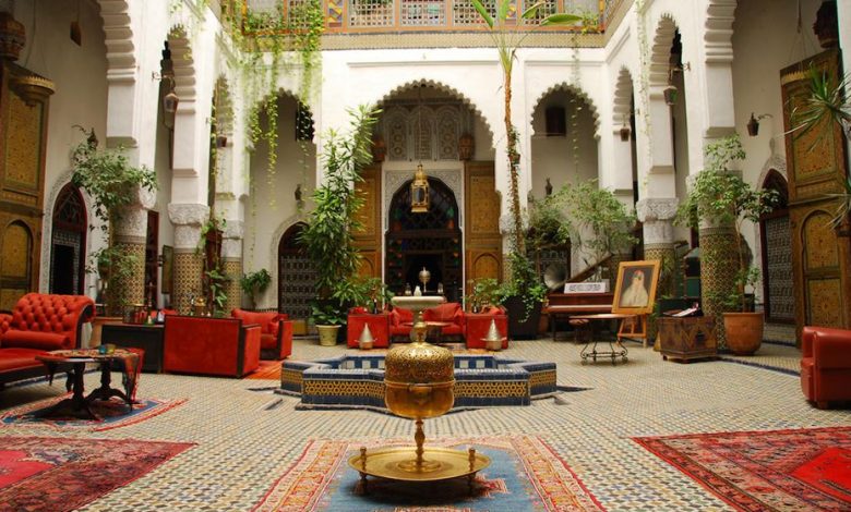 A majestic riad with some red furnitures, traditional Moroccan ithems and some decorative plants