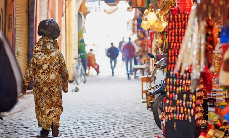 A Moroccan woman in a beautiful stylized djellaba walking in a Moroccan souk