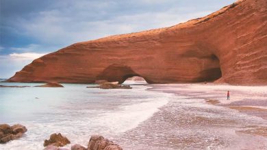 Ochre-coloured rocky arch on a wild beach of Sidi Ifni, Morocco, called Legzira Beach.