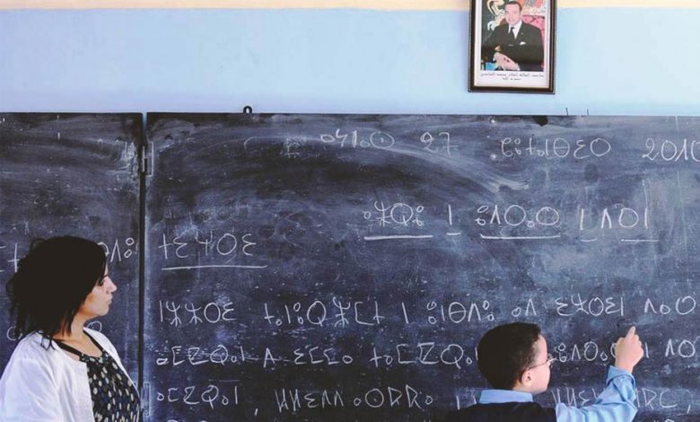 A young Moroccan student writing in Berber on a school blackboard with a Moroccan teacher by his side.