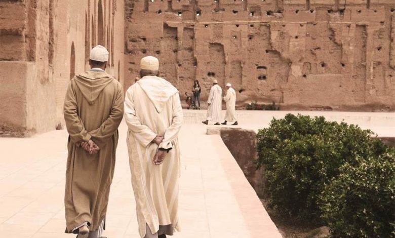 A picture from behind of two Moroccan men walking, hands behind their backs, wearing traditonnal Moroccan cloths called djellaba.