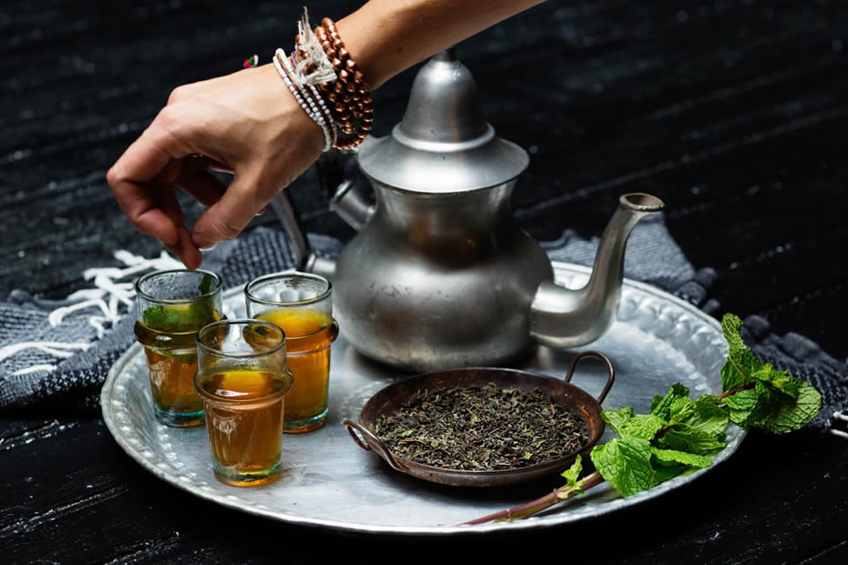 A hand putting mint in a glass where Moroccan tea was poured.